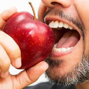 A close-up of a bearded man biting an apple