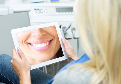 Woman looking at virtual smile design on tablet computer