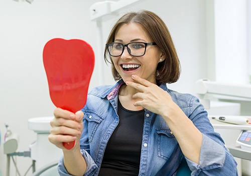 Woman looking at her smile makeover in mirror