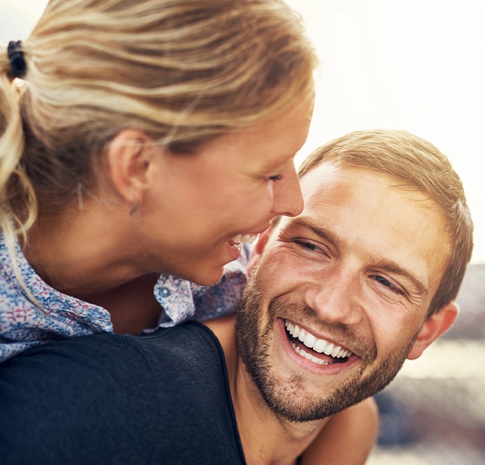 Man and woman sharing smiles after tooth replacement with dentures