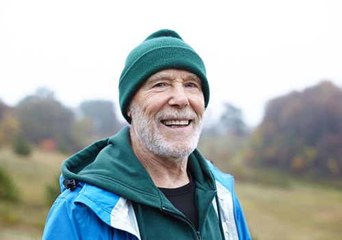 Senior man standing outside smiling on cold day