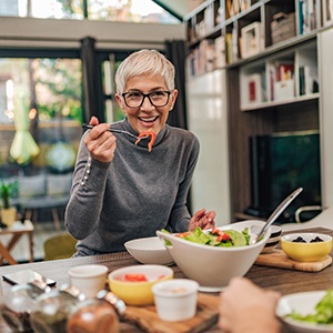 Senior woman smiling and eating a salad