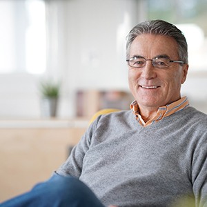 Senior man with glasses sitting on a couch