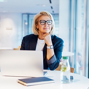 Senior businesswoman sitting at table and looking out window