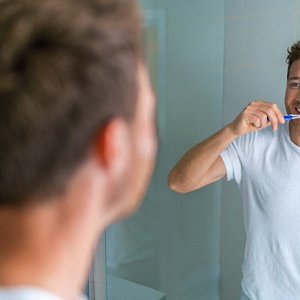 Man practicing dental implant care in Kerrville by brushing teeth