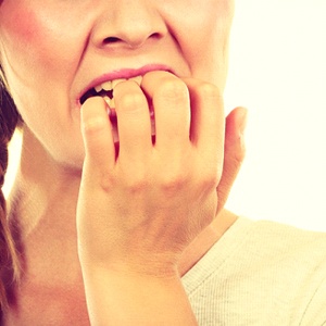 Woman with dental implants in Kerrville biting her fingernails