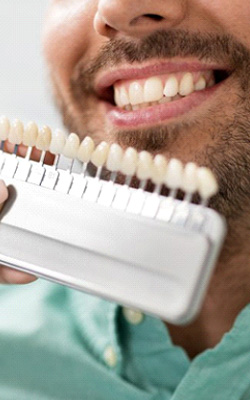Dentist comparing dental veneers to a patient’s natural teeth
