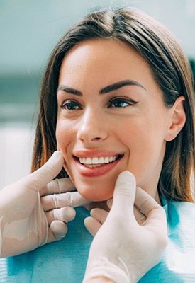 Woman smiling while dentist examines her teeth
