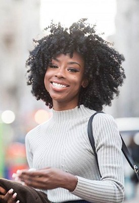 Woman smiling brightly with bustling city streets behind her