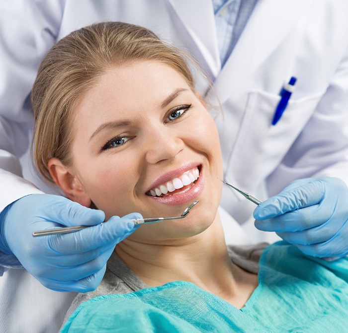 A young woman smiling while seated in the dentist’s chair preparing to have her metal-free restorations in Kerrville checked by her dentist