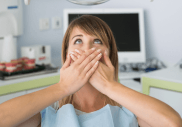 Fearful patient in need of sedation dentistry covering her mouth