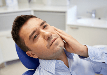 Man in need of emergency dentistry holding jaw