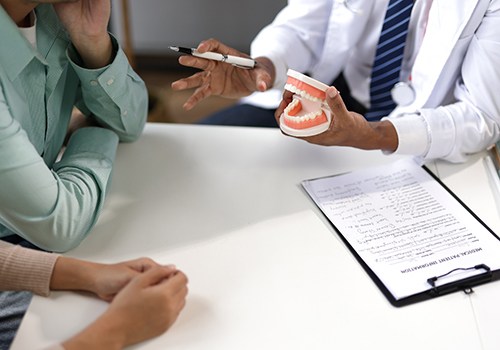 Dentist and patient sitting at table during consultation