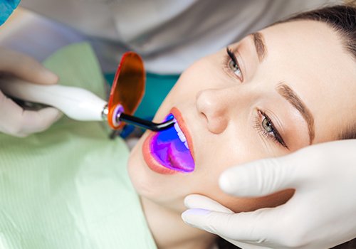 Patient's tooth-colored filling being set with curing light