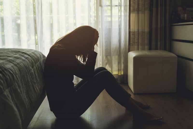 Lonely woman sitting in a dark bedroom