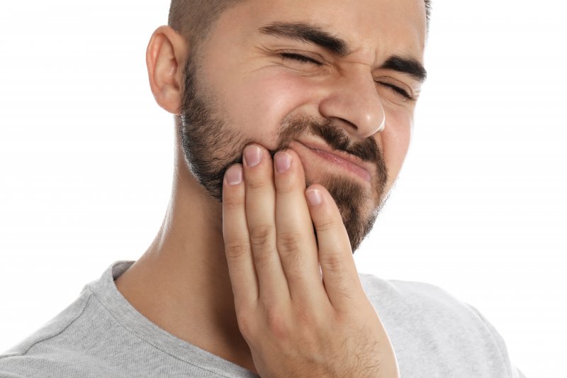 person with a dental emergency holding their cheek